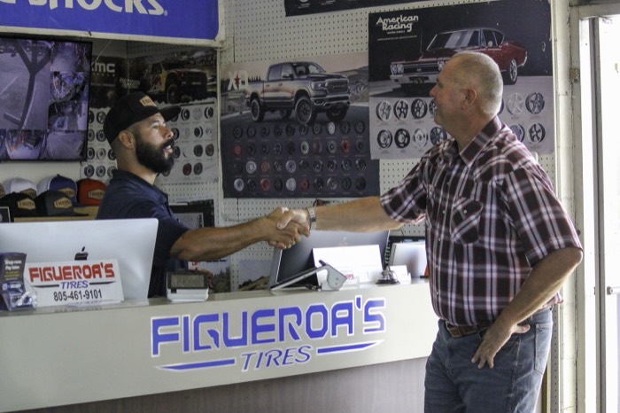 Mike Avila shaking hands with a worker across the counter at Figueroa’s Tires