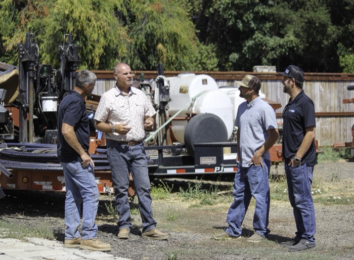Mike Avila in conversation with three workers in an equipment yard